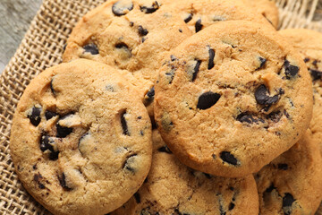 Delicious chocolate chip cookies on burlap fabric, closeup