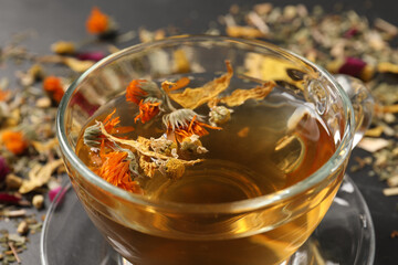 Freshly brewed tea and dried herbs on table, closeup