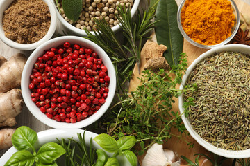 Different herbs and spices on wooden table, flat lay