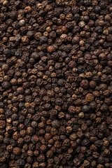 Aromatic black peppercorns as background, top view