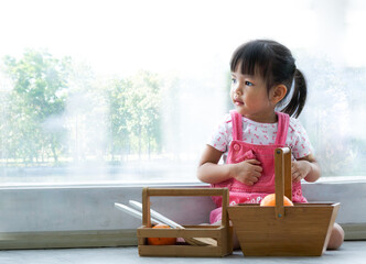 Asian girl Cute is enjoying toys on the floor in the living room by the window.