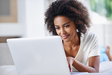 Updating her websites content. Shot of a young woman using her laptop at home.