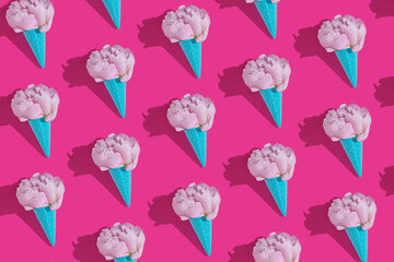 Creative blue toy ice cream cone with pink peony fluffy flower on pink minimal background with copy space flat lay. Botany idea for summer or spring wallpaper or greeting card. Seamless pattern.