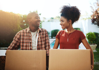 Its just you and me in our own new nest. Cropped shot of a young couple carrying boxes while moving into their new home.