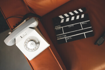 Filming some cinema movie..Vintage Brown leather armchair in loft design apartment..Old retro landline phone, sunglasses and clapperboard or clipboard.