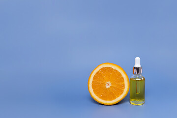 Cosmetic bottle with vitamin C serum and half an orange