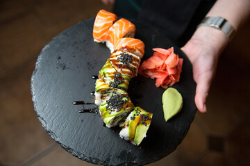Philadelphia sushi roll with salmon, cucumber, avocado, cream cheese. Sushi menu. Japanese food. On a plate. On dark background.