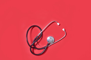 Stethoscope on red background. Theme of health care, medical treatment and disease prevention.