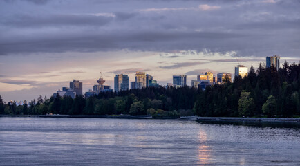 Obraz premium Seawall around Stanley Park with Highrise Buildings in background. Modern City Skyline. Downtown Vancouver, British Columbia, Canada. Colorful Sunset Sky