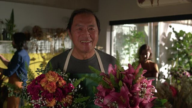 Portrait of an Asian florist holding two bouquet of flowers standing inside flower shop. Small business store entrepreneurship