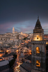 Fototapeta premium Stunning view of the illuminated village of Matera during a beautiful sunset. Matera is a city on a rocky outcrop in the region of Basilicata, in southern Italy.