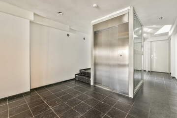 A spacious bright corridor with modern elevator and tiled floor