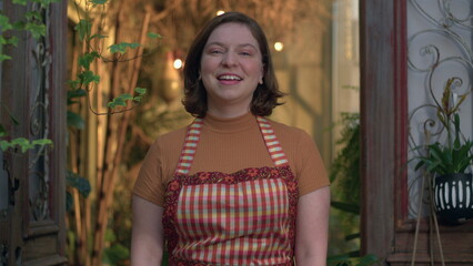 Naklejka premium Portrait of young woman employee at small business flower shop. Female entrepreneur staff wearing apron standing at local store