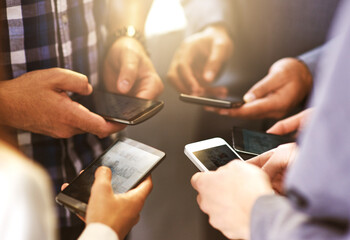 Smart phonesbusiness cards of the digital age. Shot of coworkers using their digital devices in synchronicity.