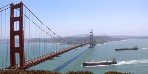 Two Cargo Ships Passing Under the Golden Gate Bridge