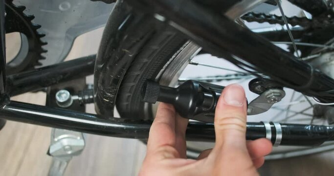 Man hand turns off the bicycle dynamo. Removes dynamo from bike tire. Close-up, indoors.