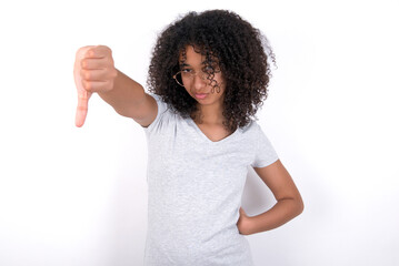 Young beautiful girl with afro hairstyle wearing gray t-shirt over white background looking unhappy and angry showing rejection and negative with thumbs down gesture. Bad expression.