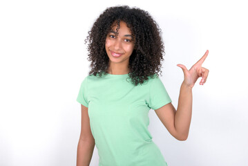 Young beautiful girl with afro hairstyle wearing green t-shirt over white background pointing up with fingers number eight in Chinese sign language B&Auml;.