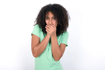 Young beautiful girl with afro hairstyle wearing green t-shirt over white background holding oneself, feels very cold outside, hopes that will not get cold