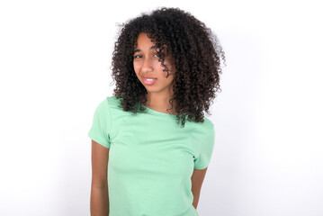 Portrait of dissatisfied Young beautiful girl with afro hairstyle wearing green t-shirt over white...