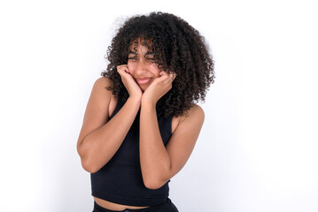 Fototapeta na wymiar Young beautiful girl with afro hairstyle wearing black tank top over white background covering ears with fingers with annoyed expression for the noise of loud music. Deaf concept.