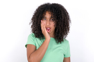 Fototapeta na wymiar Shocked Young beautiful girl with afro hairstyle wearing green t-shirt over white wall looks with great surprisment being very stunned, astonished with unexpected news, Facial expressions concept.