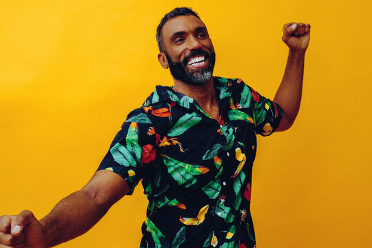 close up handsome bearded mid adult african american man smiling and dancing wearing Hawaiian shirt studio shot