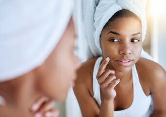 Her new skincare routine is showing results. Shot of a young woman inspecting her skin in front of...