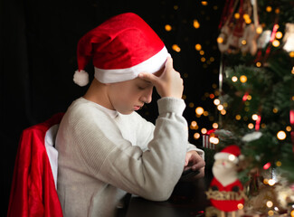 The boy wearing Santa hat sitting with his tephone