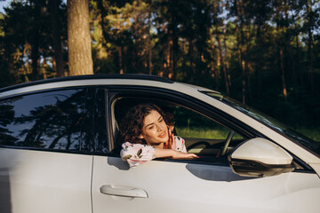 summer vacation, holidays, travel, road trip and people concept - happy smiling teenage girl or young woman in car at seaside