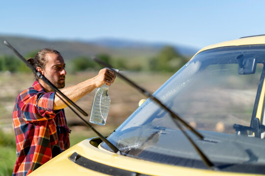 Male traveler washing car windshield