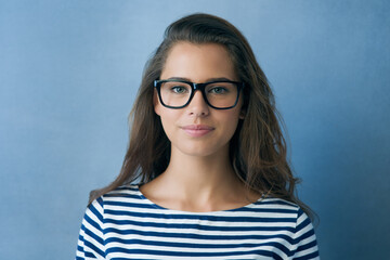 See the good. Studio shot of an attractive young woman wearing glasses.