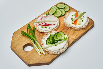 Rice cake with cream cheese and vegetables on wooden board