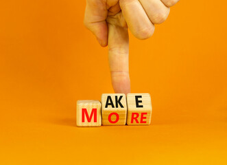 Make more symbol. Concept words Make more on wooden cubes. Businessman hand. Beautiful orange table orange background. Business, motivational quotes and Make more concept. Copy space.