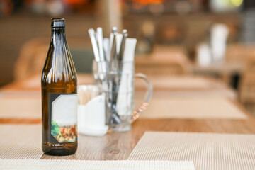 Open bottle of beer in dark glass and empty label on blurred background