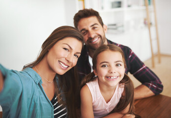 Fototapeta premium This family isnt selfie shy. Portrait of a happy married couple and their young daughter posing for a selfie together at home.
