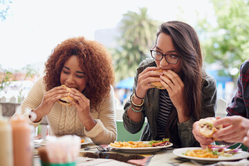 This is the best place in town. Cropped shot of a friends eating burgers outdoors.