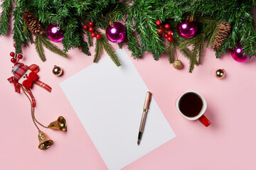 Christmas background with peper surrounded by Christmas decorations and a cup of coffee on pink backgraund. Letter to Santa or Christmas shopping list