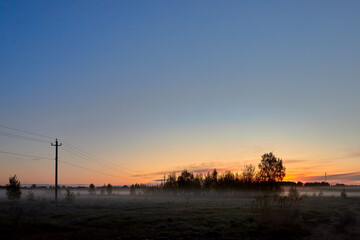 Field in the early foggy morning at sunrise. Amazing nature in early foggy morning on sunrise. Early morning landscape with the first rays of the sun.