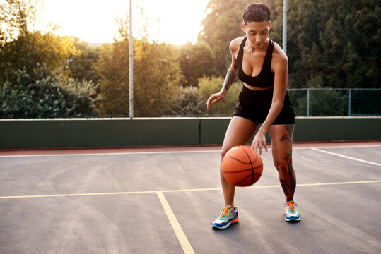 Warming up is essential. Full length shot of an attractive young sportswoman standing alone on a basketball court and warming up with the ball. - Powered by Adobe