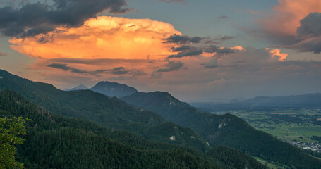 Cumulus clouds at sunset with the view over the valley and mountains.
