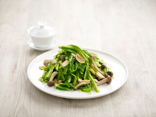 Stir-fried Chinese Chives and Wild Mushrooms with Garlic with chopsticks served in a dish isolated on mat side view on grey background