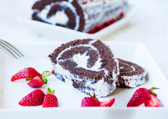 Gentle pieces of sponge cake roll with white cream and fresh strawberries for tea.