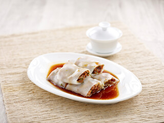 Steamed Rice Rolls with BBQ Pork Filling with chopsticks served in a dish isolated on mat side view on grey background