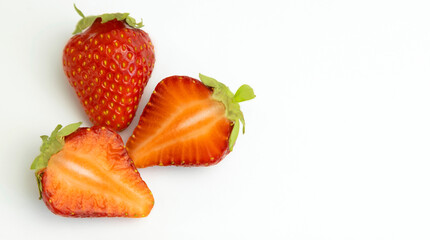 Juicy strawberries and two halves. Strawberries isolated on a white background. Place for text.