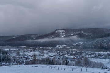 Terrible black sky before a snowfall. Beautiful landscape of a mountain winter village. Weather forecast