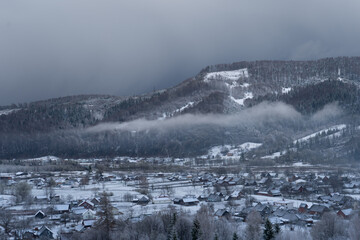 Terrible black sky before a snowfall. Beautiful landscape of a mountain winter village. Weather forecast