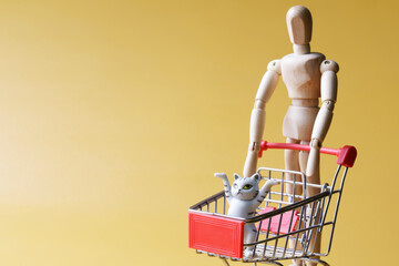 A lone anthropomorphic mannequin carries a cute funny kitten in a cart from a supermarket. The...