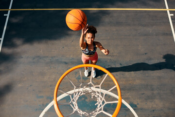 Practice like youve never won, play like youre never lost. High angle shot of a sporty young woman throwing a basketball into a net on a sports court.