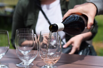 Person pouring rose wine into glasses